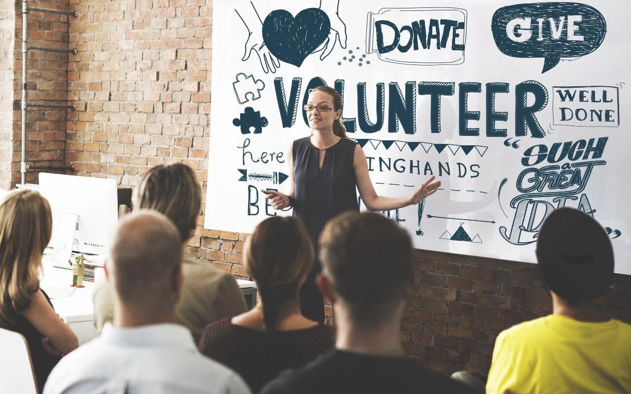 A volunteer meeting in front of a hand-drawn chalkboard