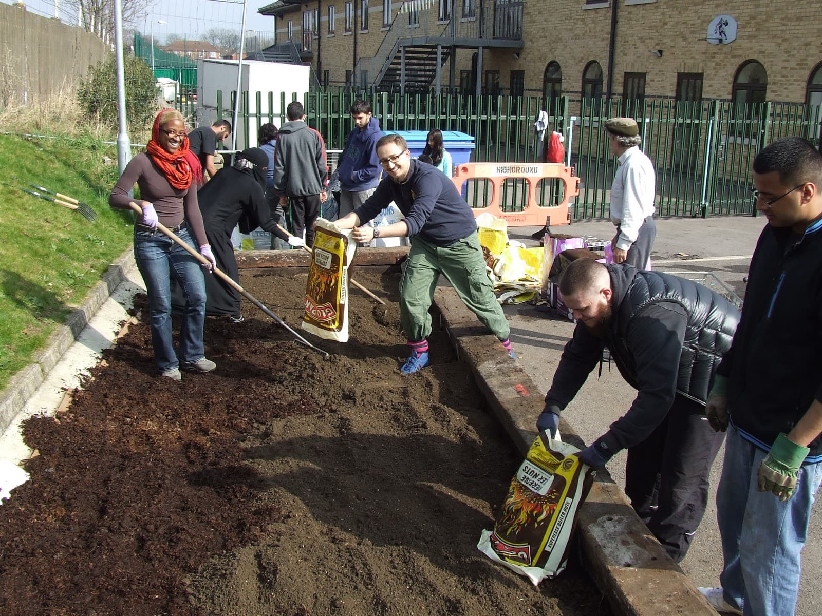 Neighbours digging and planting a community garden bed